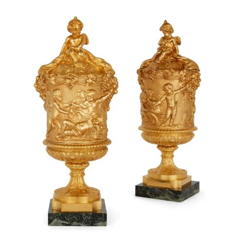 A pair of Louis XVI style ormolu urns in the style of Clodion